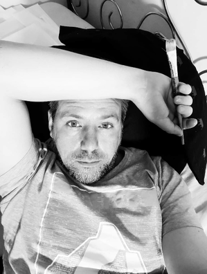 Künstler Ronny Reinecke im Bett mit Pinsel in der Hand und macht Pause